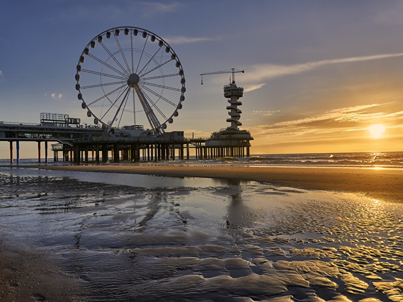 Pier van Scheveningen met de ondergaande zon en het reuzenrad op de pier op de achtergrond
