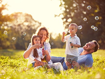 Familie lachend in een park met bellenblazend kind