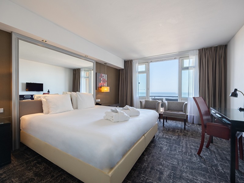 Superior room in Grand Hotel Amrâth Amsterdam with a large double bed, a desk, a sitting area with a table, and a view over the canals