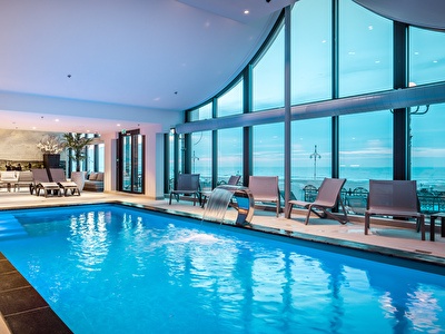 Wellness zwembad met ligbedden langs de rand en uitzicht op de Noordzee